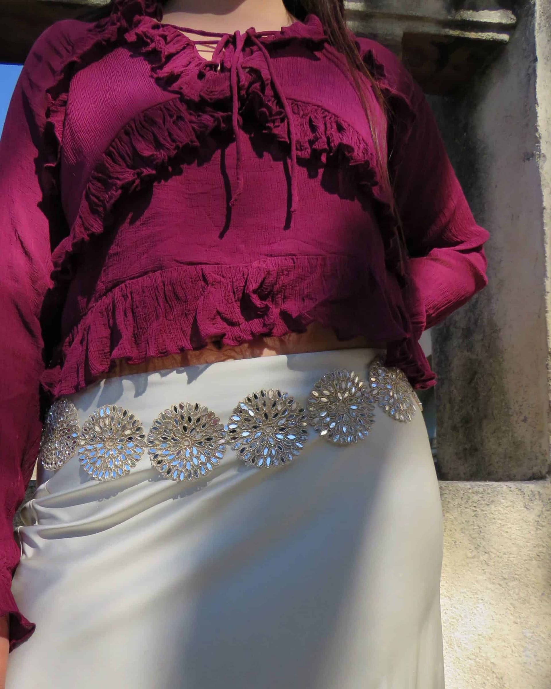 Vestido de fiesta con detalles brillantes y blusa de manga larga en color burdeos.