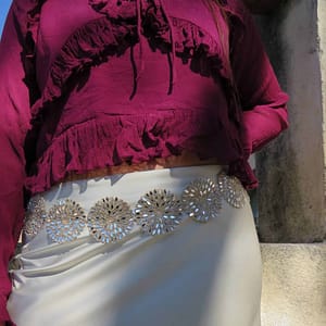 Vestido de fiesta con detalles brillantes y blusa de manga larga en color burdeos.